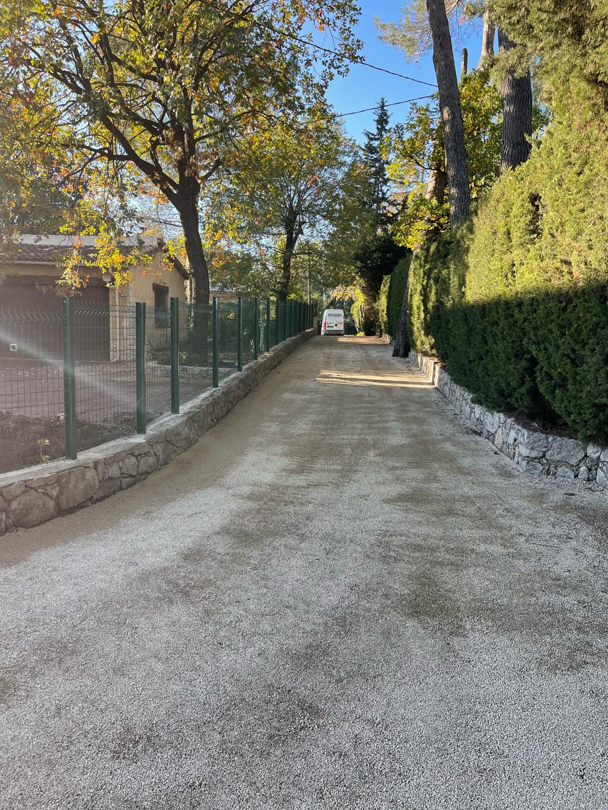 Chemin d'accès en bicouche gravillonné clair entre murets de pierre