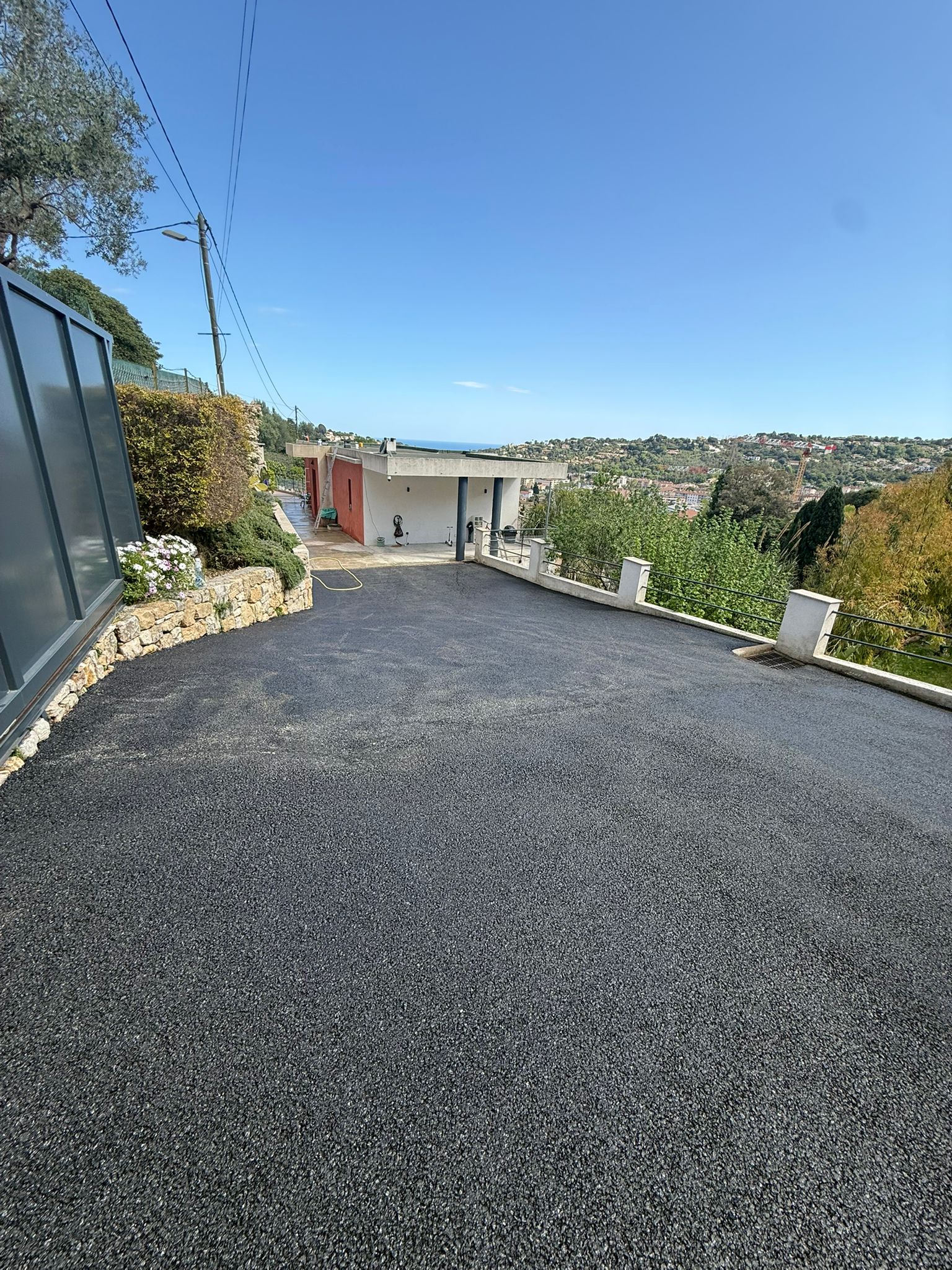 Cour avec accès garage en enrobé noir et carport